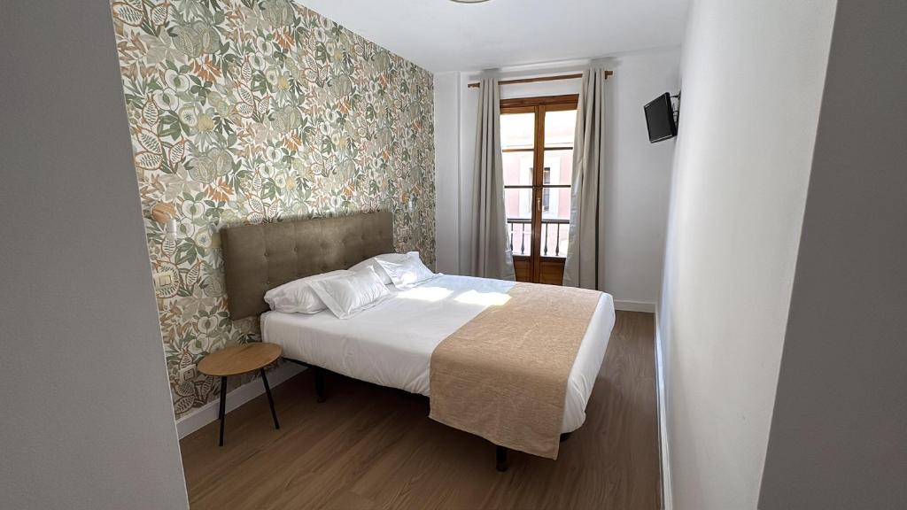 a small bedroom with a bed and a window at Pensión Argüelles in Ribadesella