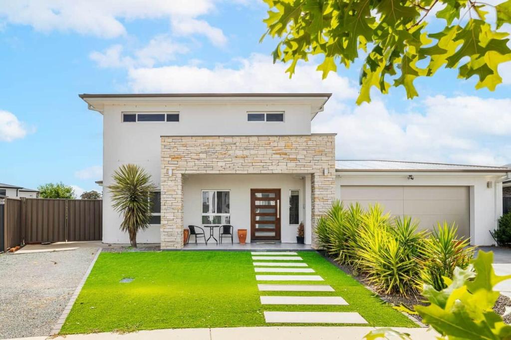 a white house with a garage and grass at Charming 5-Bedroom House in Harrison