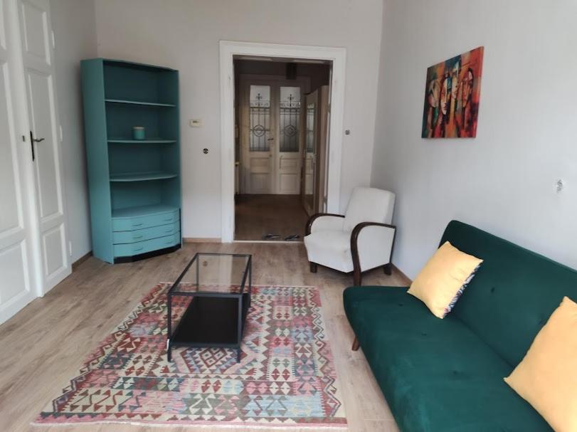 a living room with a green couch and a glass table at Sunny side apartman in Sopron