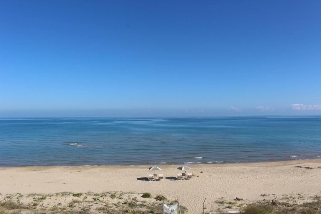 plaża z dwoma parasolami i oceanem w obiekcie Dimore di Mare w mieście Termoli