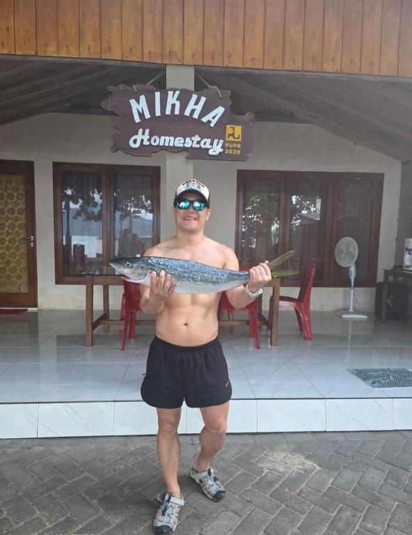 a man holding a fish in front of a restaurant at Mikha Homestay BUNAKEN in Manado