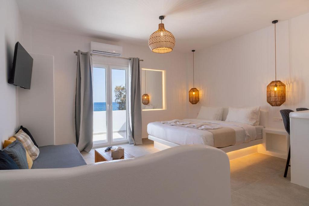 a white bedroom with a bed and a couch at Aqua Cozy Suites in Perissa