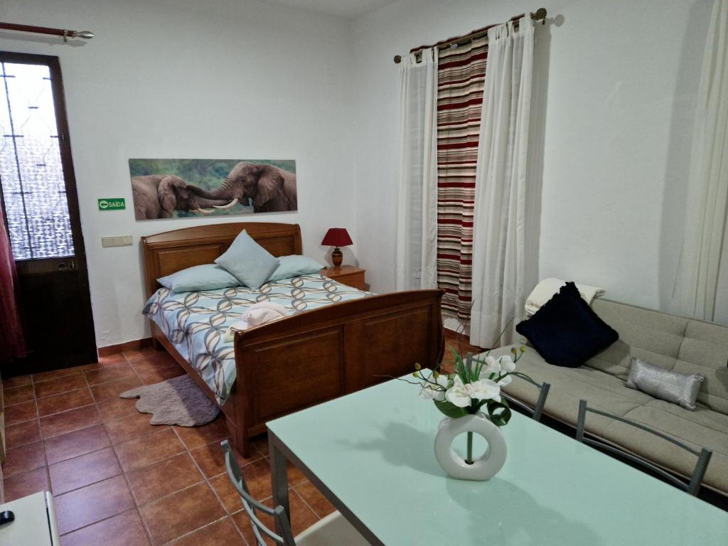 a bedroom with a bed and a couch and a table at Casa Vanda, Machico in Machico