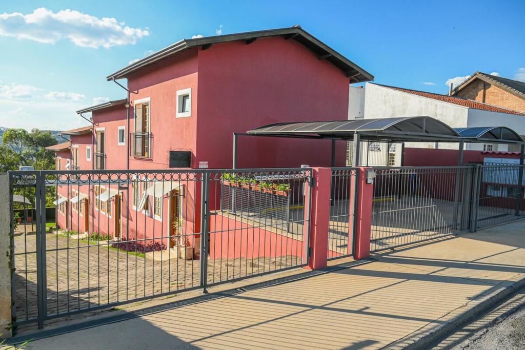 a red fence with an umbrella in front of a building at Vila dos Pinheiros 1 in Serra Negra