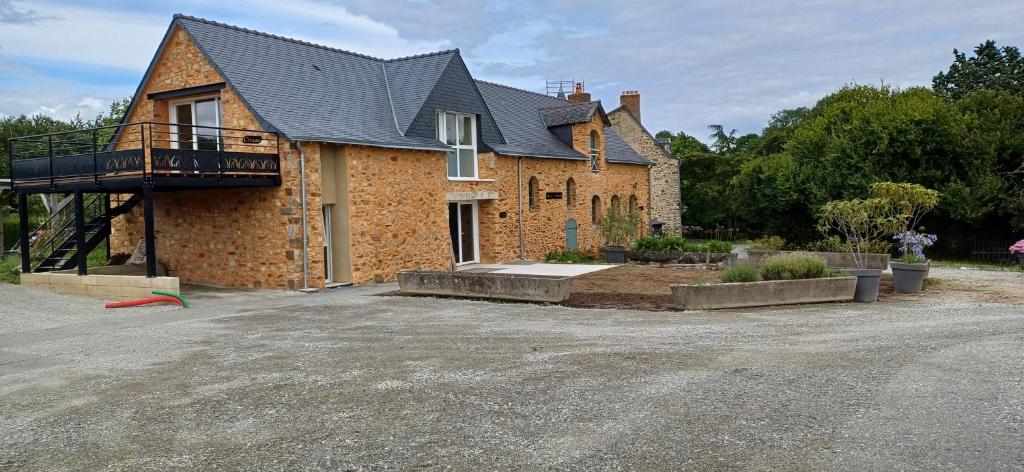 a brick house with a balcony on top of it at Logis de la Provosterie CLICRO in Ahuillé