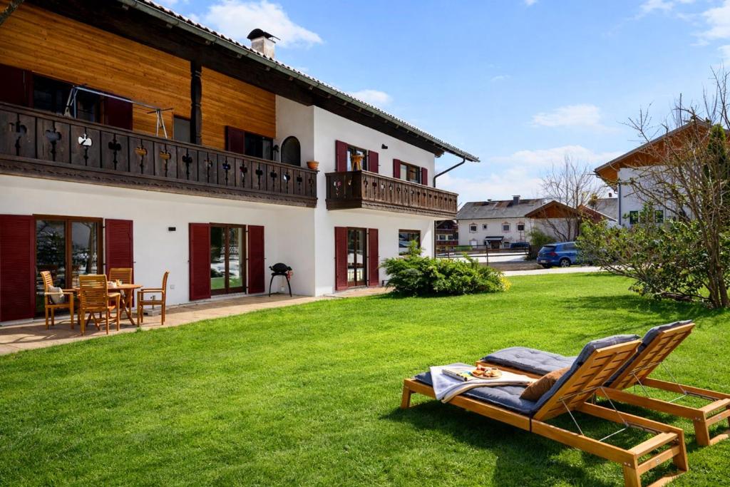 a yard with two lawn chairs in front of a house at Alpenpanorama Bad Kohlgrub in Bad Kohlgrub