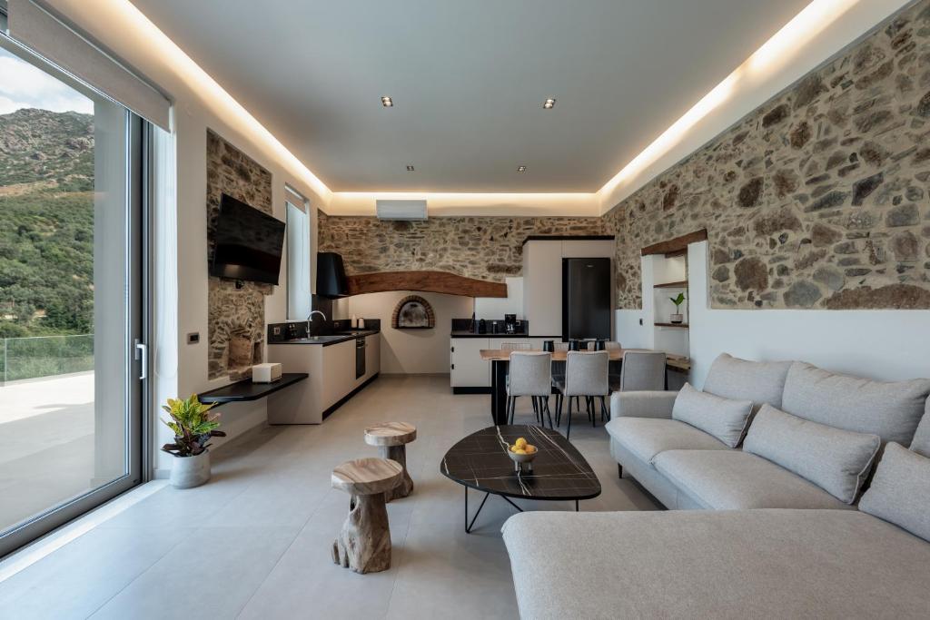a living room and kitchen with a stone wall at Villa Afroditi - Sfinari in Áyios Nikólaos