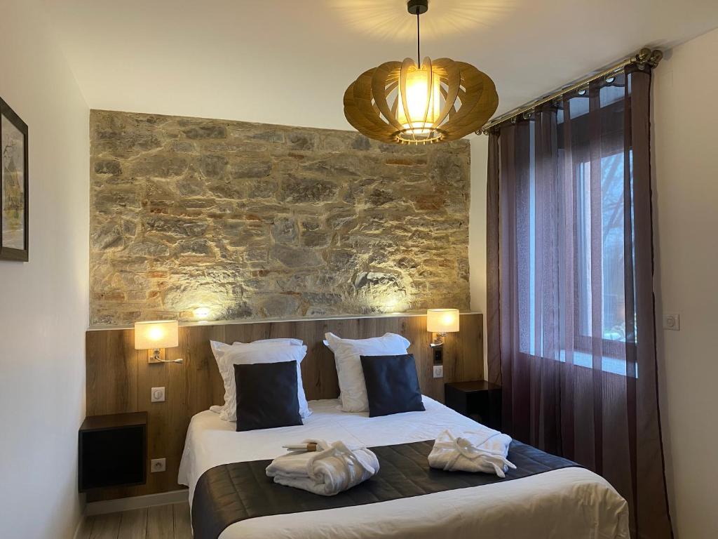 a bedroom with a large bed with a stone wall at Le Moulin d'Oscar & Spa - Mulhouse Nord in Baldersheim