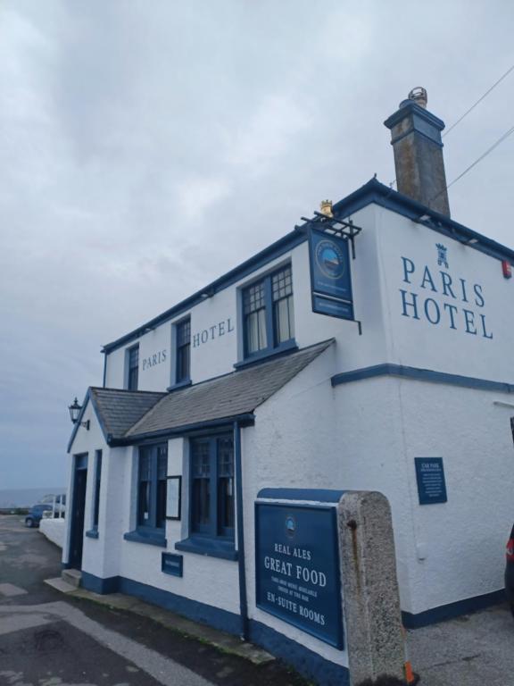 a white building with a sign in front of it at The Paris Hotel in Coverack