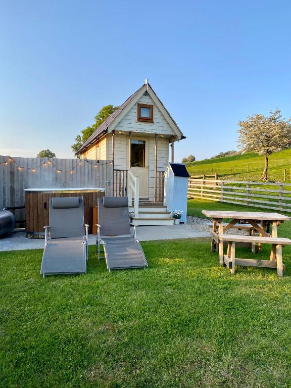 a group of chairs and a table and a house at The Niblet Bonnie View Glamping Cabins, Helmsley in Carlton