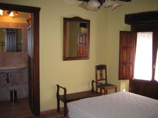a bedroom with a bed and a mirror and a chair at Casa Rural Los Boteros in Pesquera de Duero