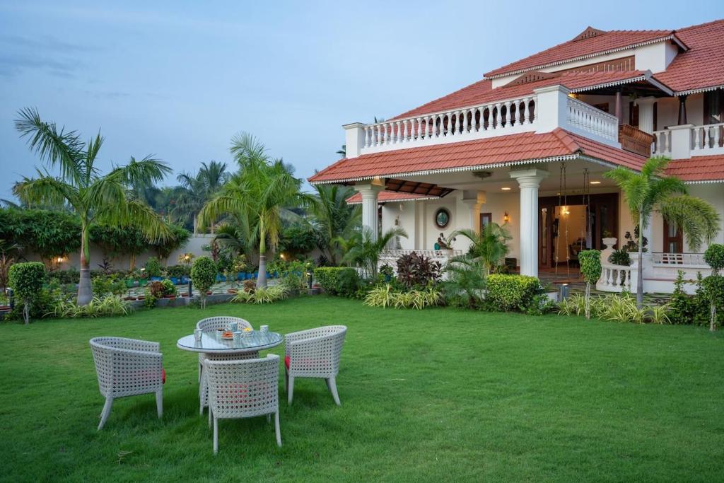 a table and chairs in front of a house at The Palmyrah - A LuxUnlock Private Villa in Mahabalipuram