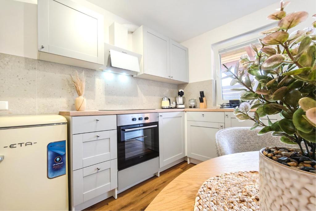 a kitchen with white cabinets and a stove and a table at Red Maple Apartments in Maribor