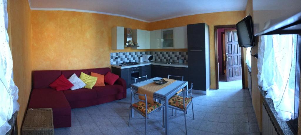 a living room with a red couch and a kitchen at Casa Camilla CIR 0058 in Aosta