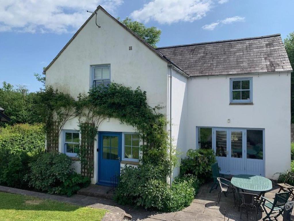 a white house with a blue door and a table at 3 Bed in Gower oc-hh472 in Cheriton