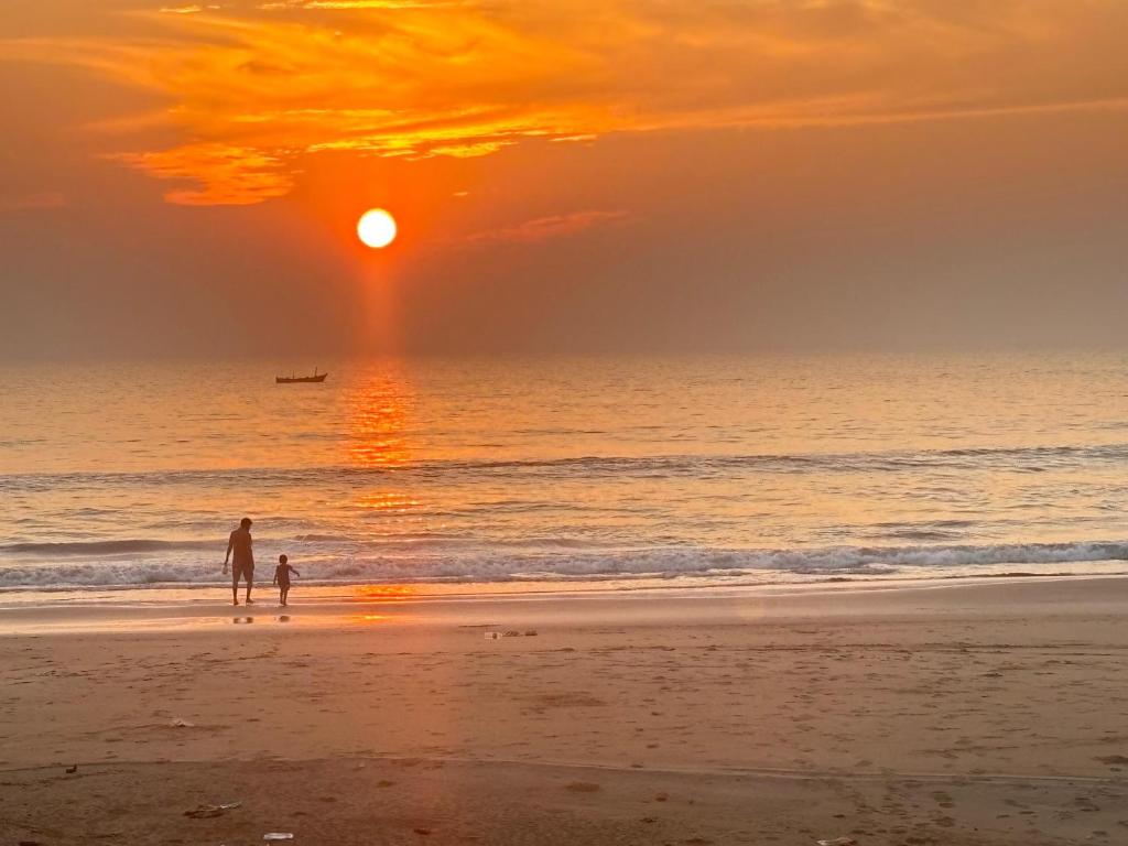 a man and a child walking on the beach at sunset at Gokarna Beach Vibes in Gokarn