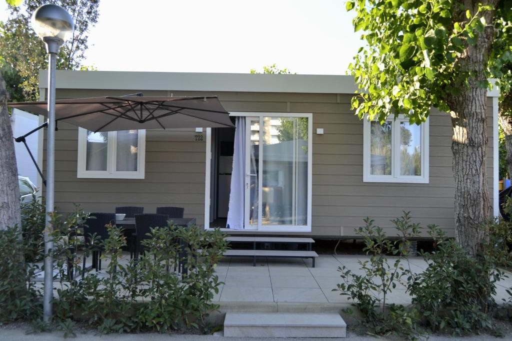 a house with a patio with an umbrella at Camping 4 Cerchi Ecogreen in Lido di Fermo
