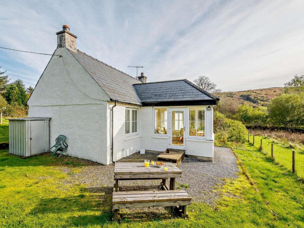 a small white house with a picnic table in front of it at 2 Bed in Strontian oc-ca046 in Scotstown