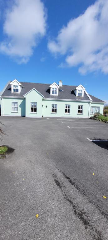 a large white house with a parking lot at Dubhlinn House Accommodation in Doolin