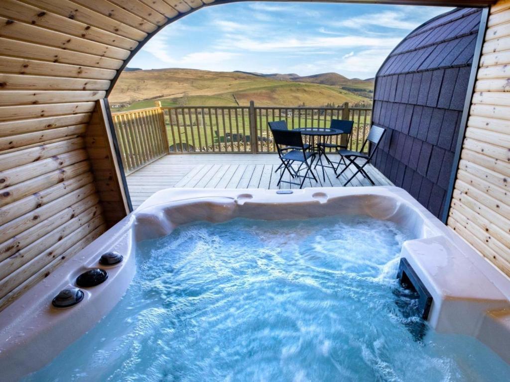 a hot tub on a deck with a table and chairs at 1 Bed in Hawick oc-75347 in Hawick