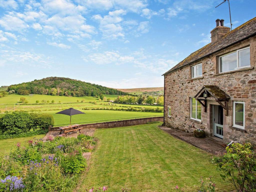 an external view of a stone house with an umbrella at 3 Bed in Penrith oc-94982 in Pooley Bridge