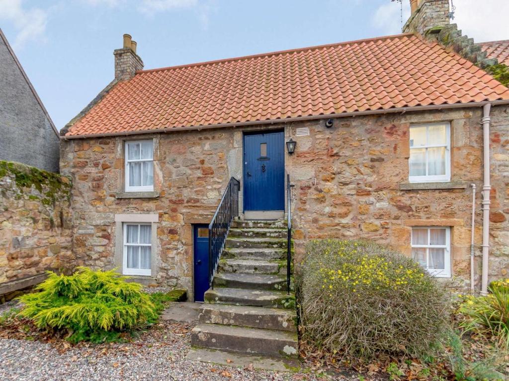 a stone house with a blue door and stairs at 2 Bed in Anstruther oc-ca006 in Crail