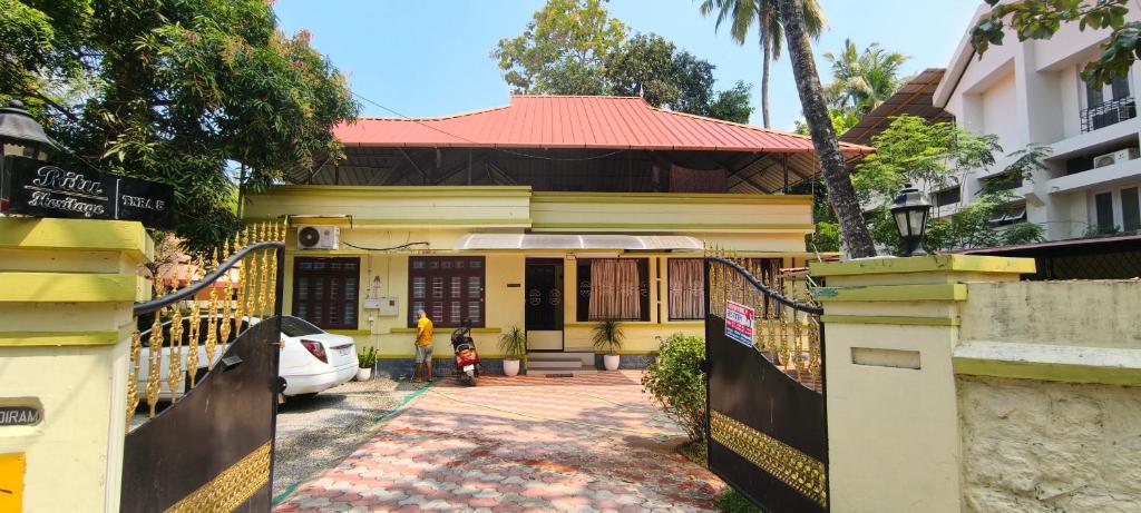 a yellow house with a woman standing in front of it at Ritu Heritage Homestay in Trivandrum