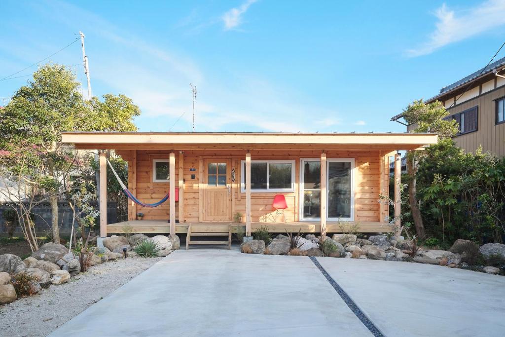 a small wooden house with a driveway at Banksia Seaside Cottage in Ōami
