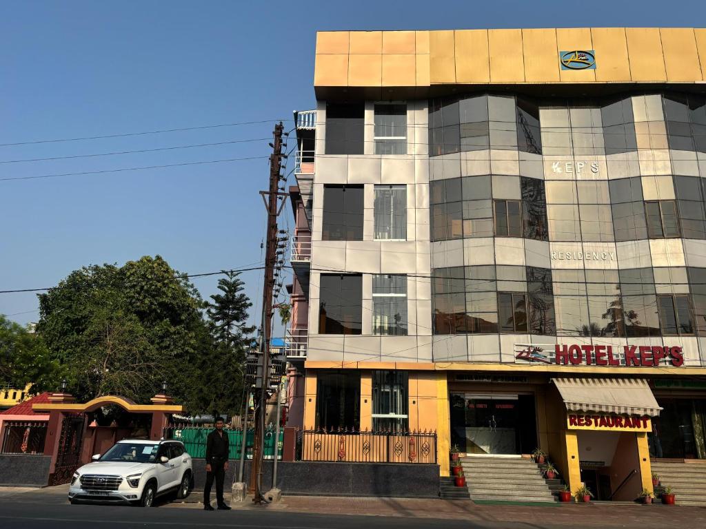 a white car parked in front of a building at Hotel Kep's - A Business Class Hotel in Contai