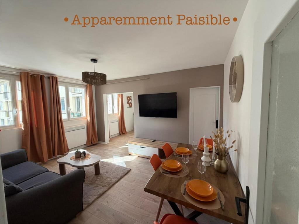 a living room with a table and a tv at Appartement paisible in Limoges