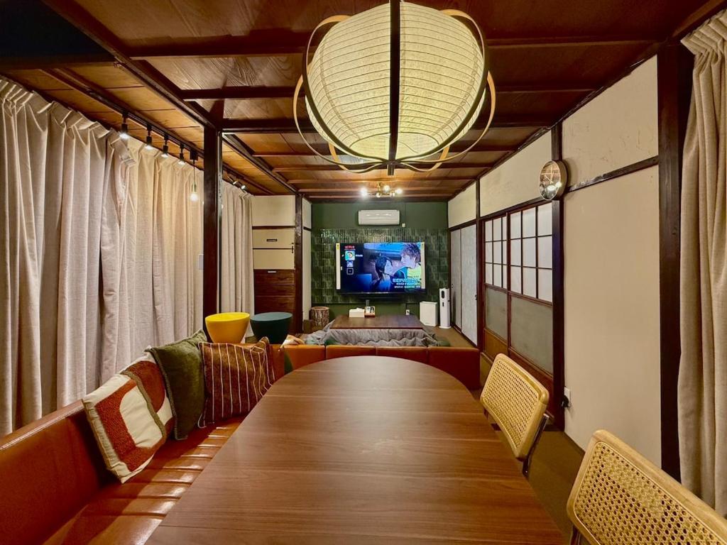 a room with a long table with chairs and a television at 一棟貸し宿 maicca2 in Numazu