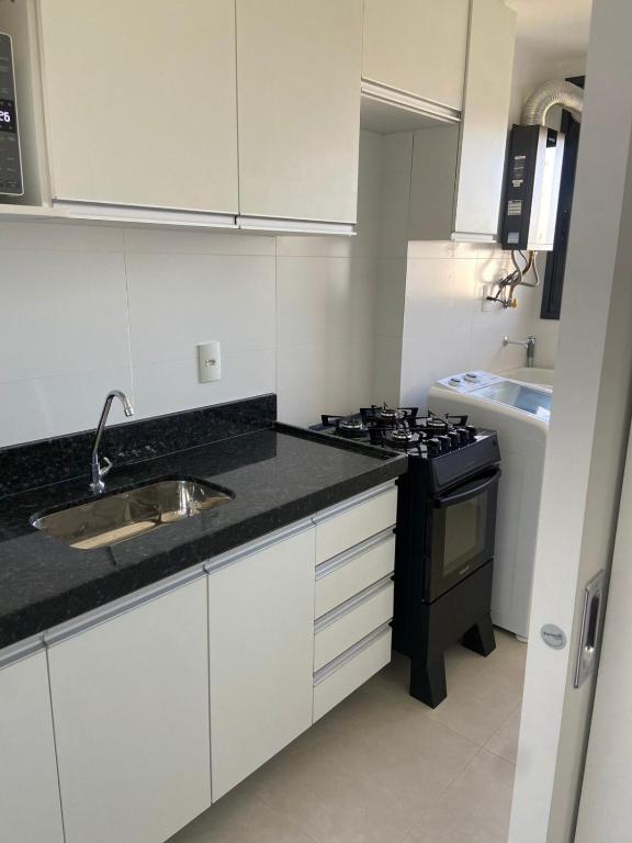 a white kitchen with a sink and a stove at Vila confort in Vila Velha
