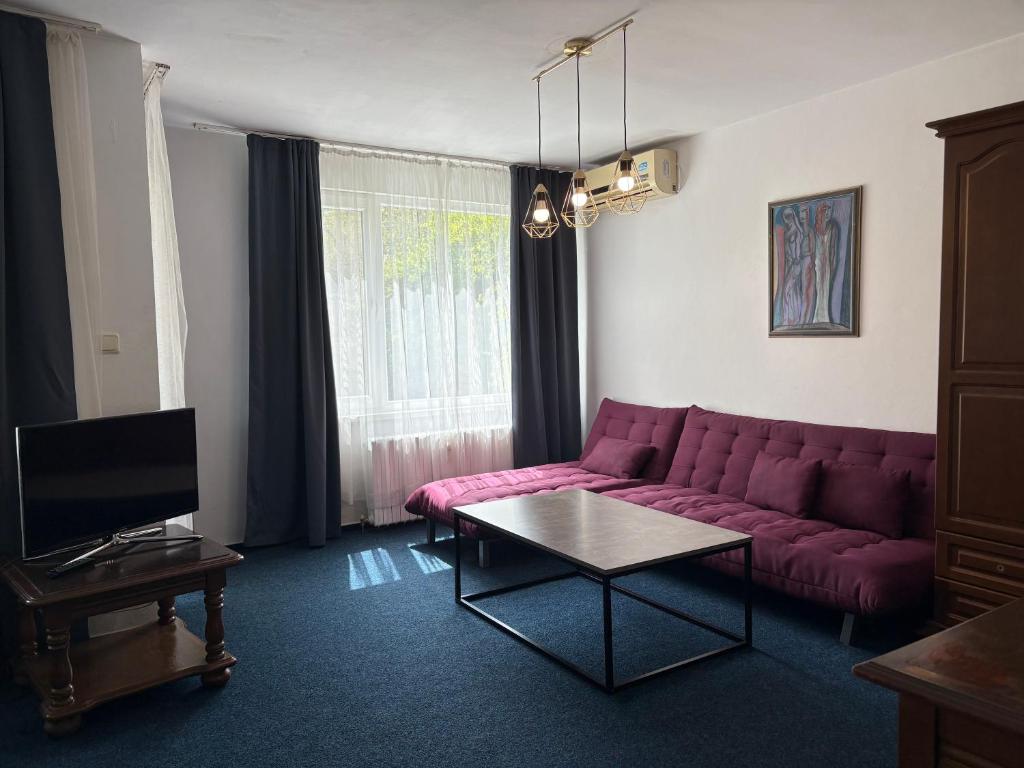 ein Wohnzimmer mit einem lila Sofa und einem Tisch in der Unterkunft Hotel Rotasar in Sofia