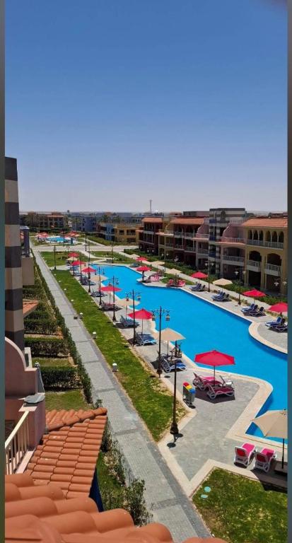 a large pool with red umbrellas in a resort at بورتو مطروح - القبطان in Marsa Matruh