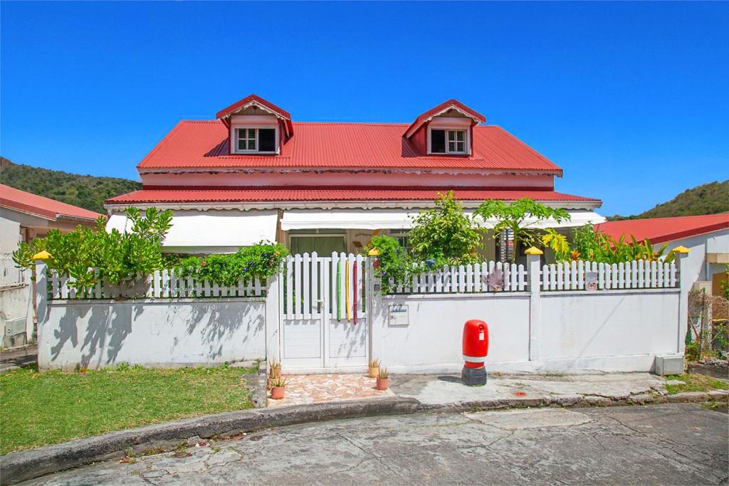 a house with a white fence and a red roof at LA DILETTANTE - Maison Créole de 130m2 - Clim - Tout à Pied in Terre-de-Bas