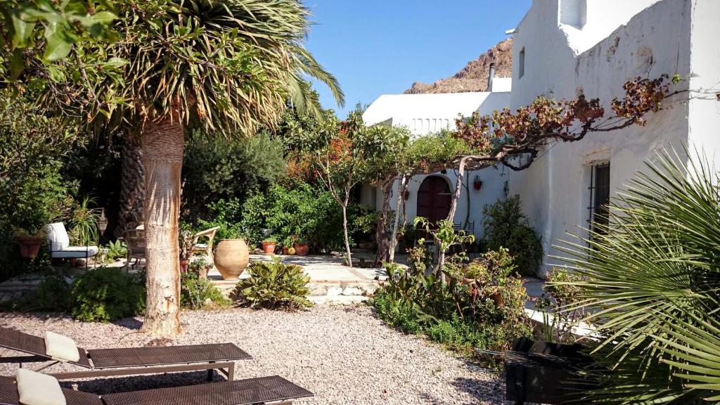 un jardín con palmeras y un edificio blanco en Cortijo el Grillo, en Níjar