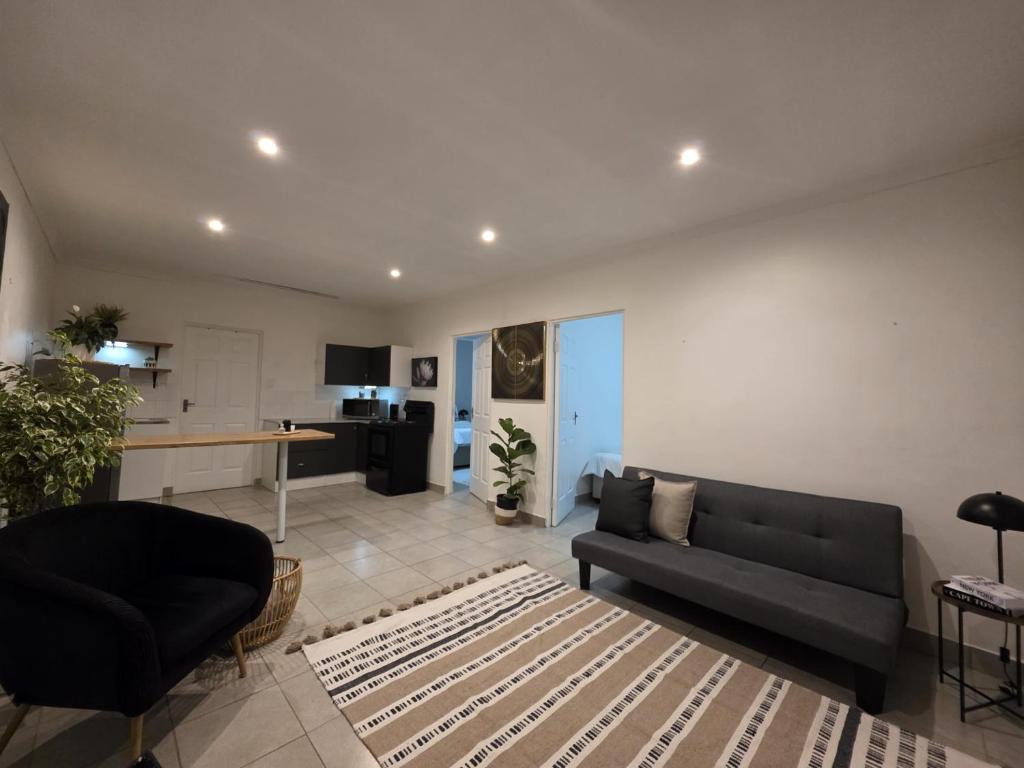 a living room with a couch and a kitchen at The041Stay in Gqeberha