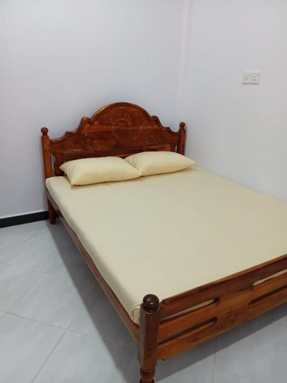 a wooden bed with two pillows on it at Ocean waves in Trincomalee