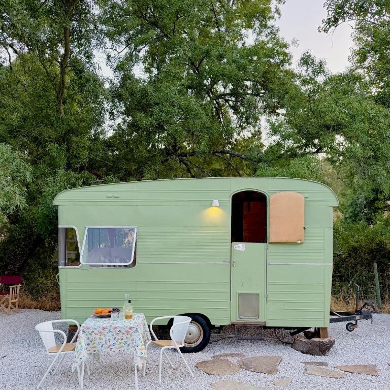 a green trailer with a table and chairs at Olívia, Caravana Vintage, Castelo de Vide in Castelo de Vide