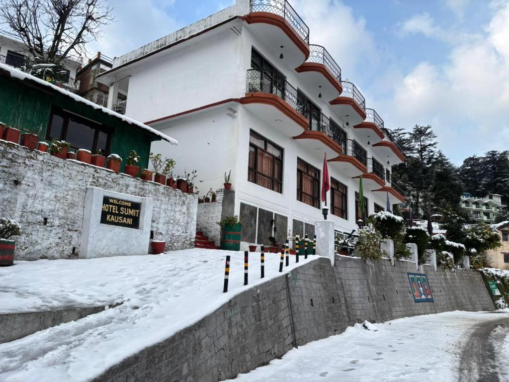 a building with snow in front of it at Hotel Sumit in Kausani