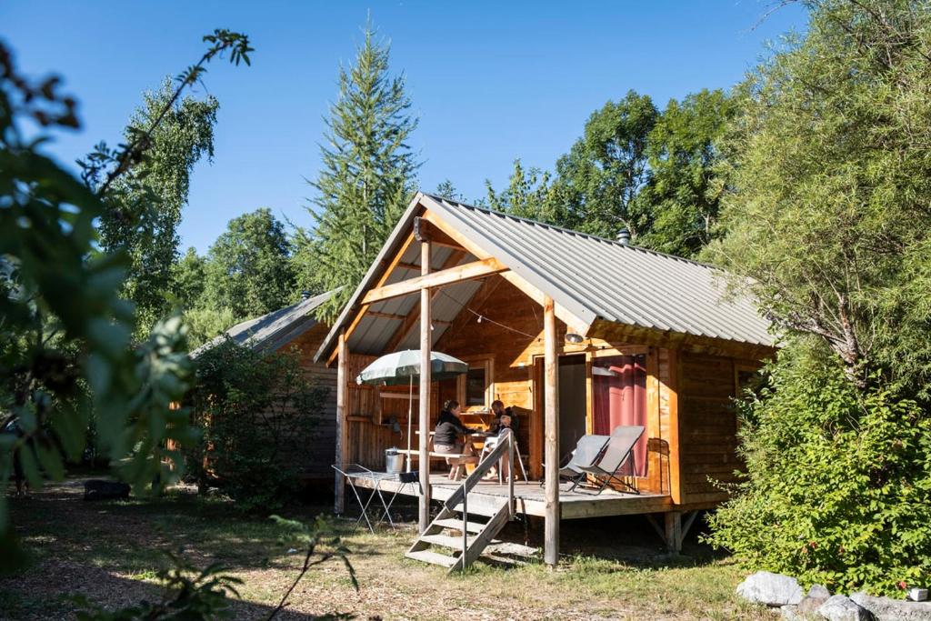 a small wooden cabin with a porch in a forest at Huttopia Vallouise in Vallouise