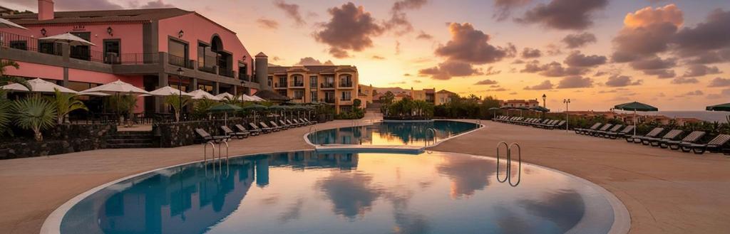 a resort swimming pool with a sunset in the background at Hotel-Apartamento Las Olas in Los Cancajos