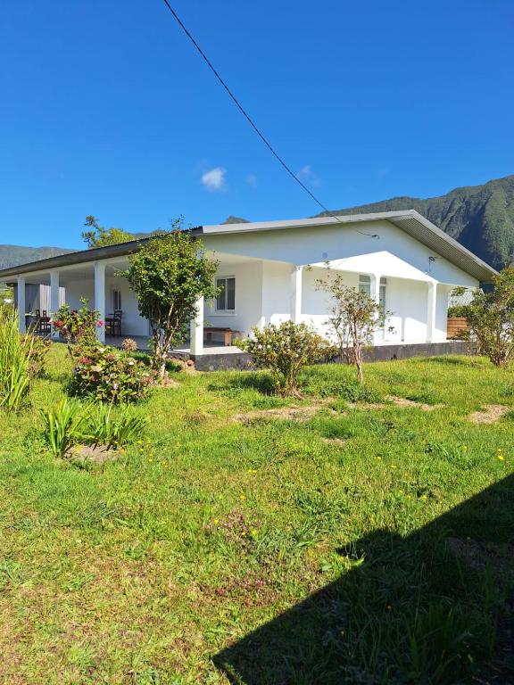 a white house with a green lawn in front of it at Villa Goyavier in La Plaine des Palmistes