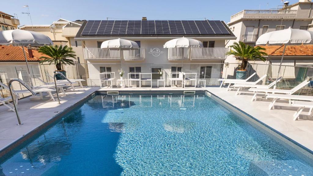 a swimming pool with chairs and a building at Almara Green Hotel in Rimini