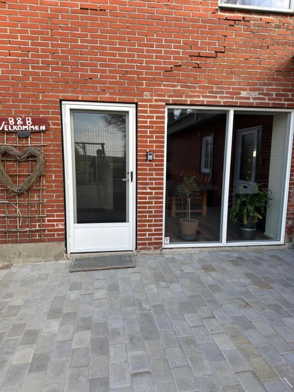 a white door on a brick building with two windows at Højmosegård ÅBENT HEMS in Varde