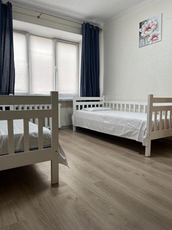a bedroom with two beds and two windows at Затишна трьохкімнатна квартира у Львові in Lviv