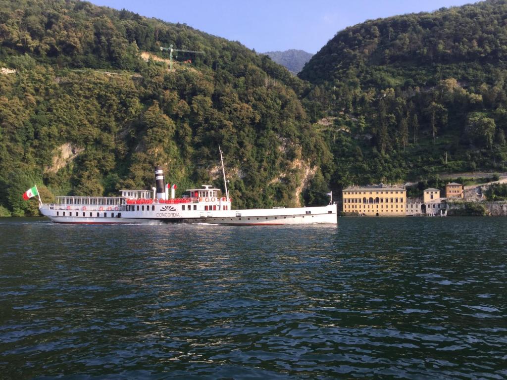 a large boat on the water near a mountain at Como Luxury Rooms in Como