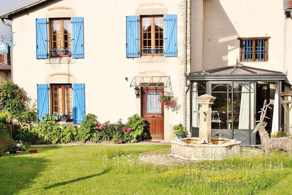 a house with a fountain in the yard at Chambre Fleur bleue, les Volets Bleus in Laneuvelotte