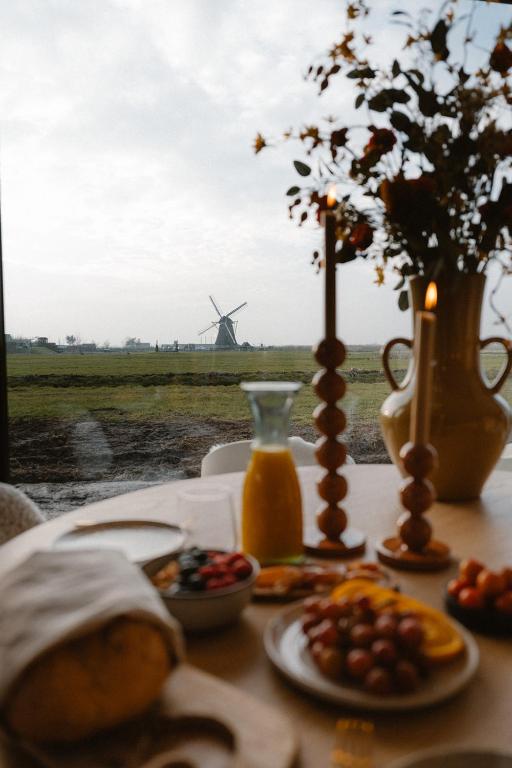 a table with plates of food and a windmill in the background at Polderlodge de Verademing in Goudriaan