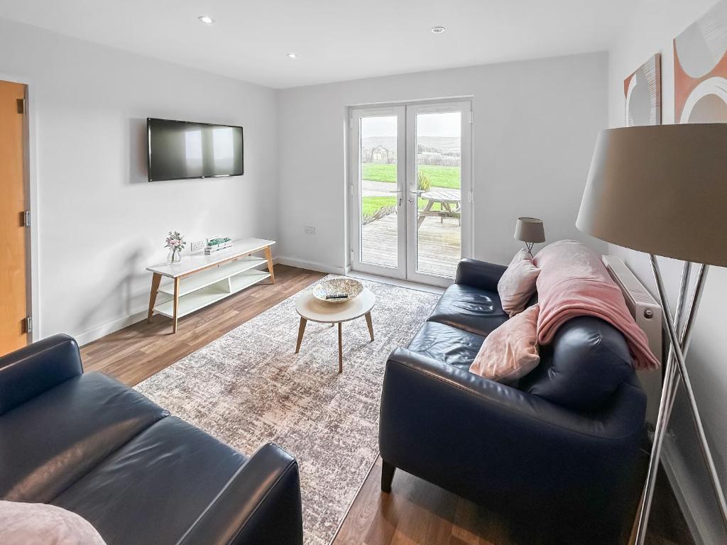 a living room with a black leather couch and a table at Magnolia Lodge - Uk51603 in Peel